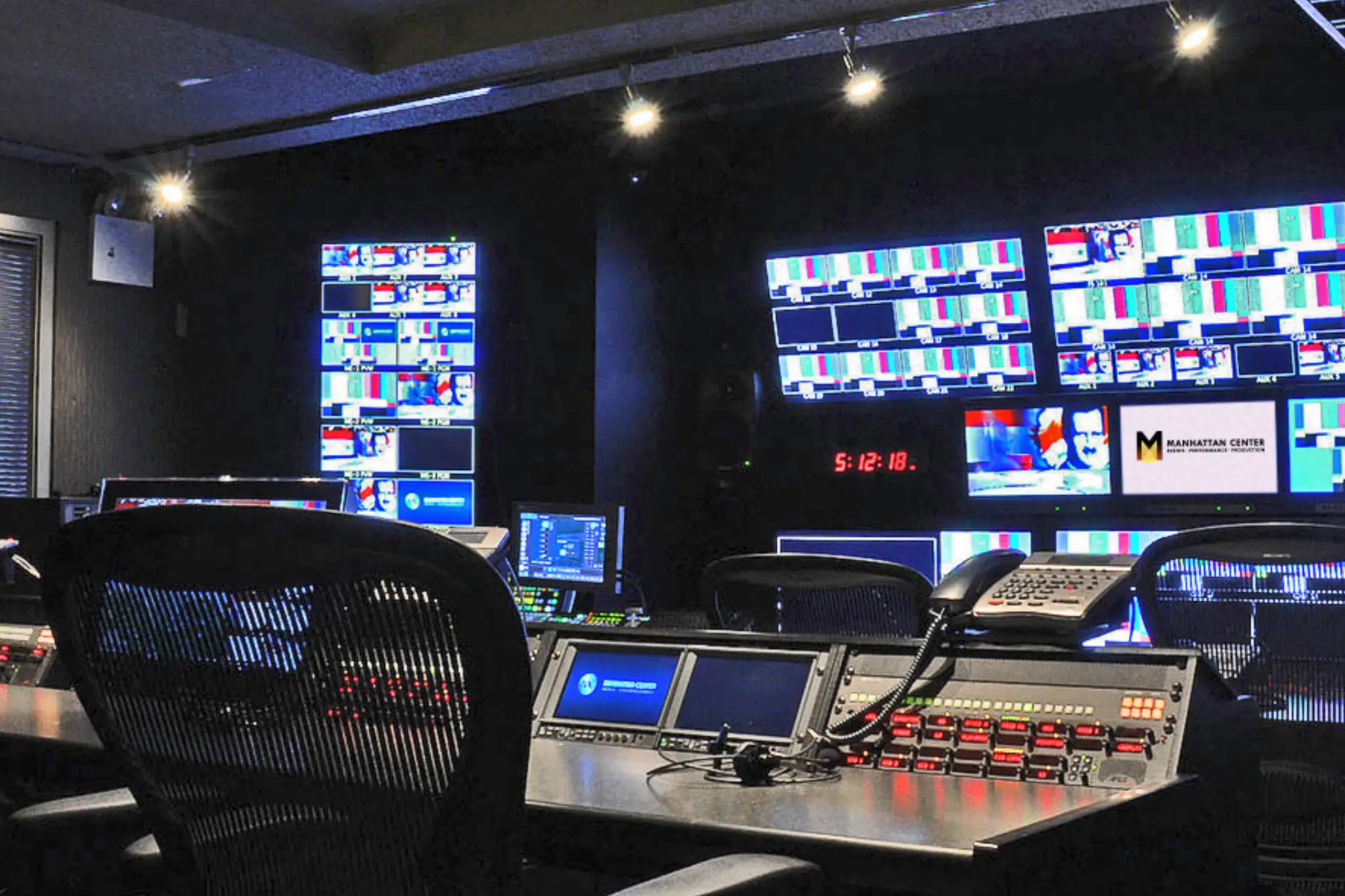 A modern audio control room featuring a large mixing console, multiple screens, sound equipment, and a swivel chair A modern audio control room featuring a large mixing console, multiple screens, sound equipment, and a swivel chair
